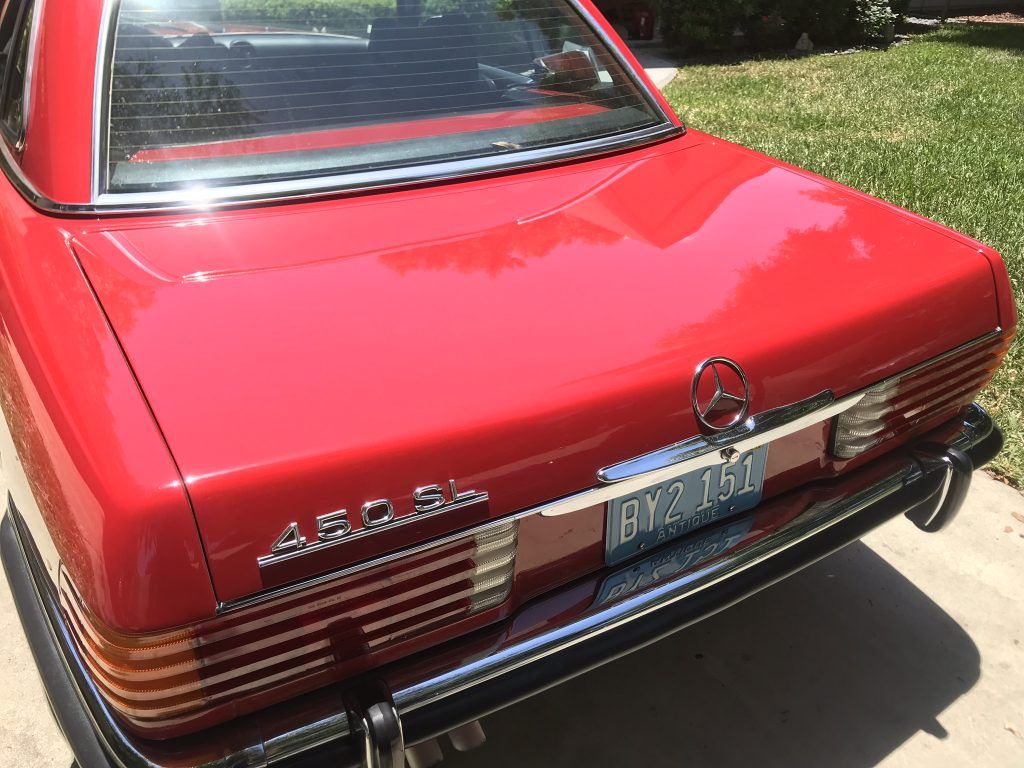 A red mercedes benz is parked in a driveway.