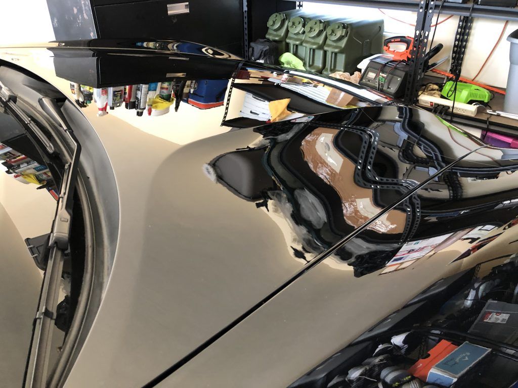 A car is parked in a garage with its hood open.