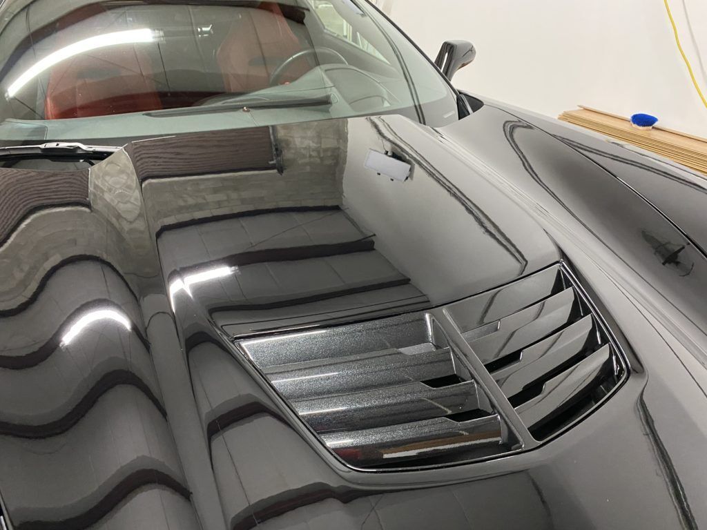 A car is sitting in a garage with the hood open.