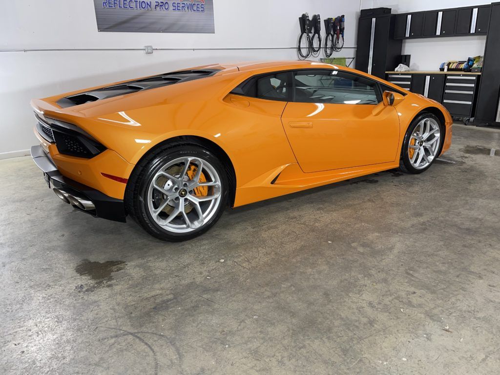 An orange lamborghini huracan is parked in a garage.
