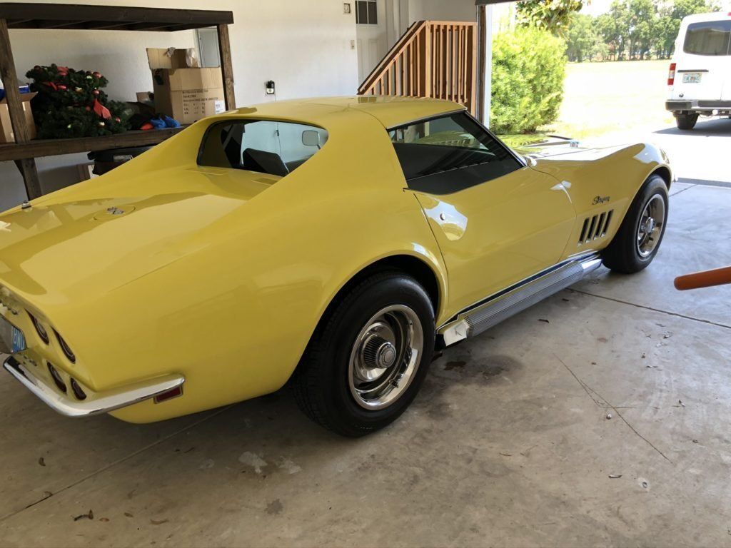 A yellow corvette is parked in a garage.