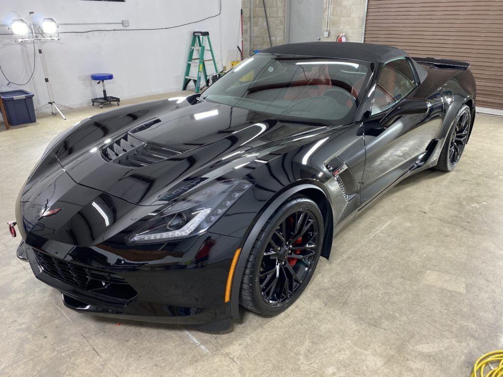 A black sports car is parked in a garage.