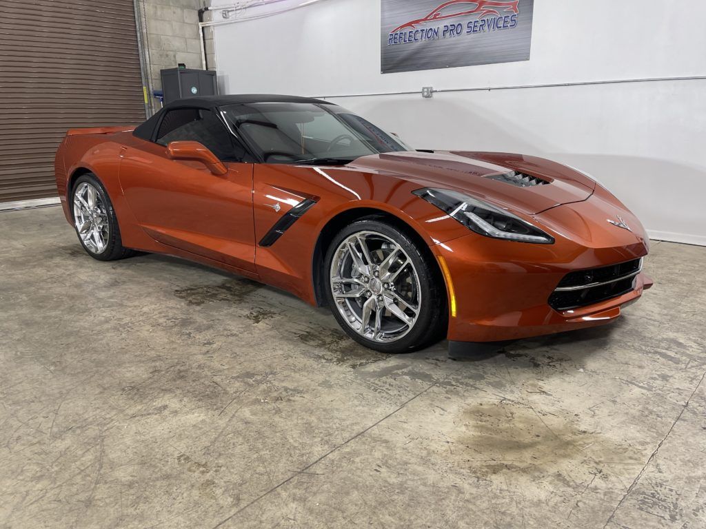 A red corvette convertible is parked in a garage.