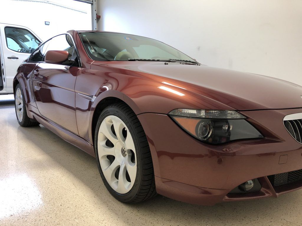A red car with white wheels is parked in a garage