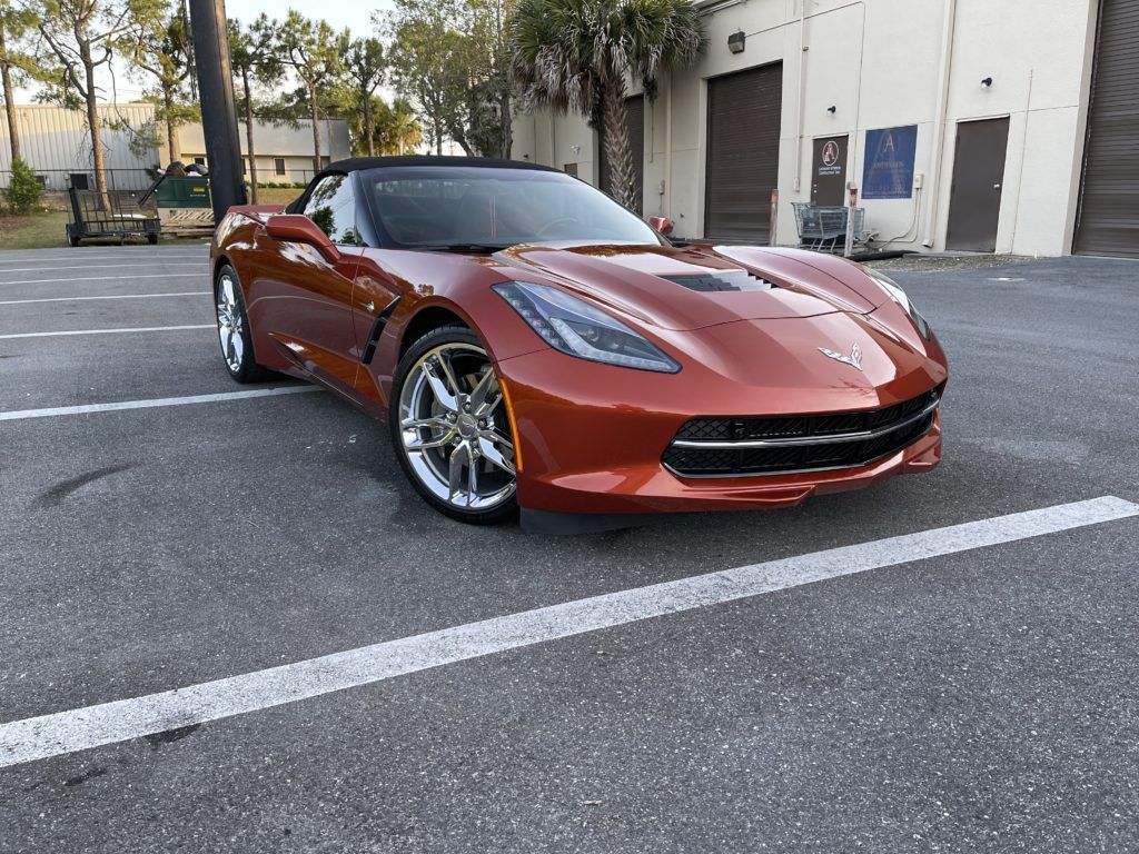 A red corvette convertible is parked in a parking lot.