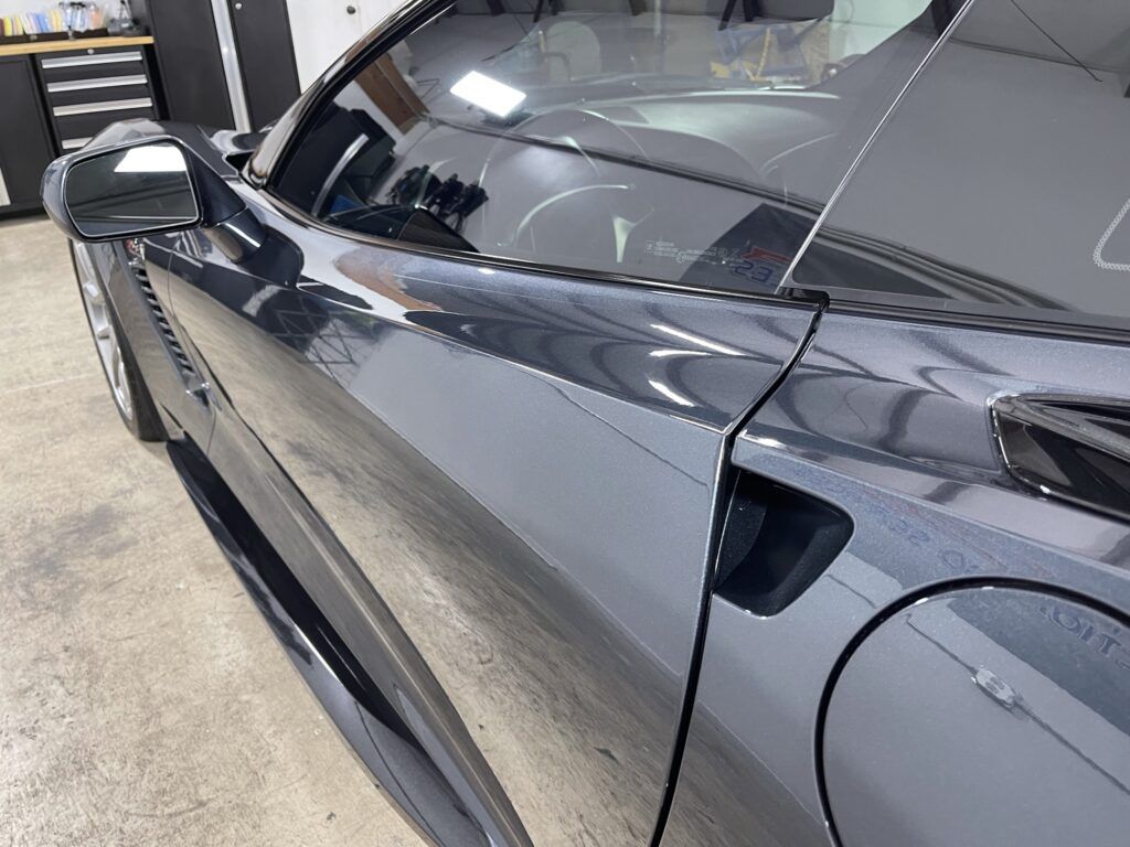 A black sports car is parked in a garage.