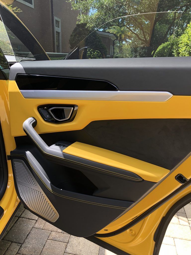 The door of a yellow lamborghini urus is open.