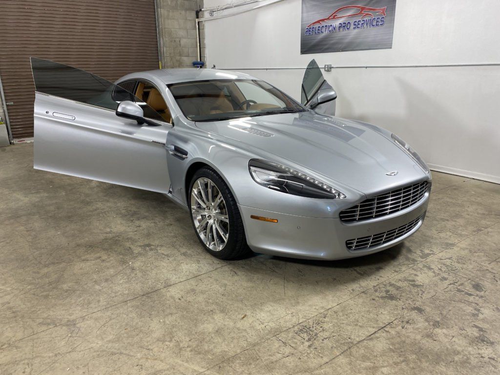 A silver sports car is parked in a garage with its doors open.