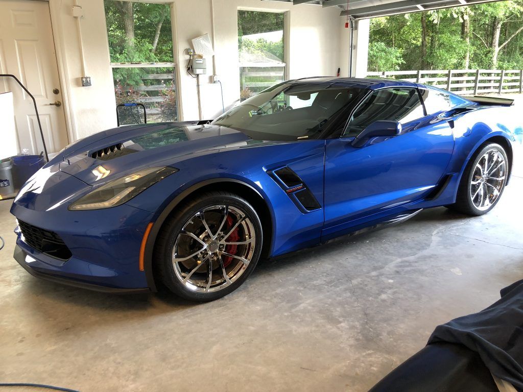 A blue corvette is parked in a garage.
