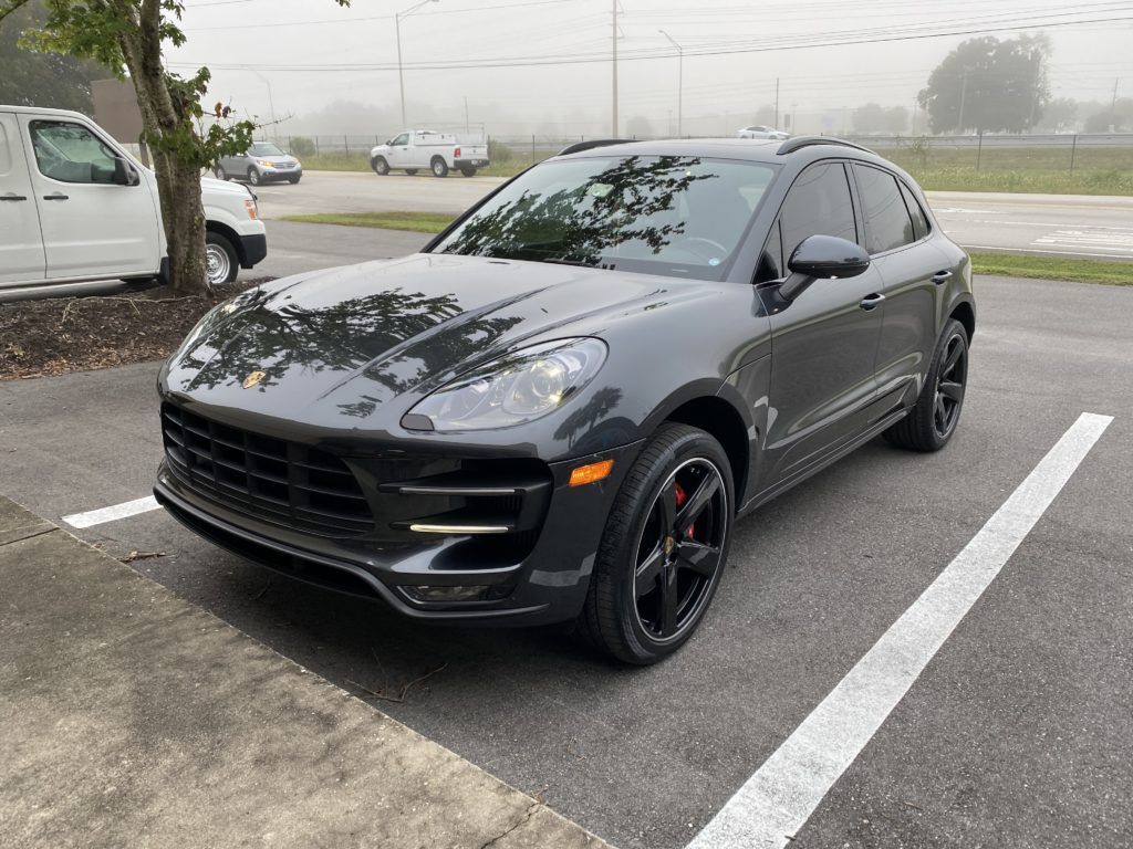 A black porsche macan turbo is parked in a parking lot.
