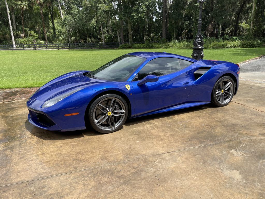 A blue ferrari 488 gtb is parked in a driveway.