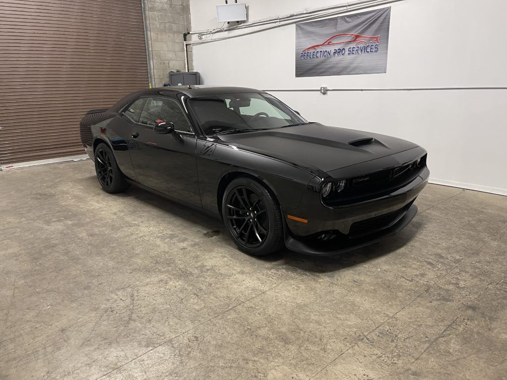 A black dodge challenger is parked in a garage.