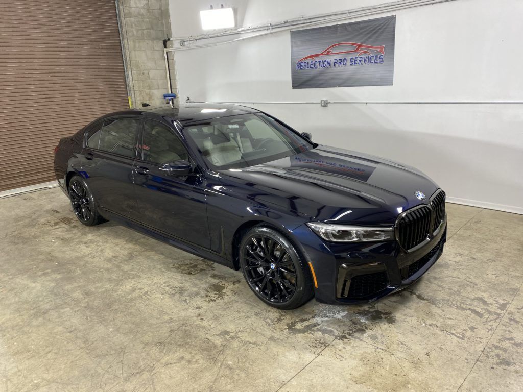 A black bmw 7 series is parked in a garage.