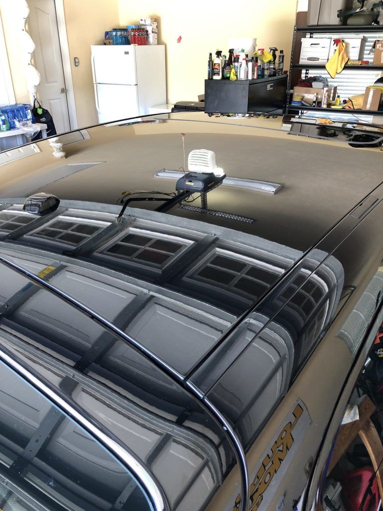 A car with a roof rack is parked in a garage.