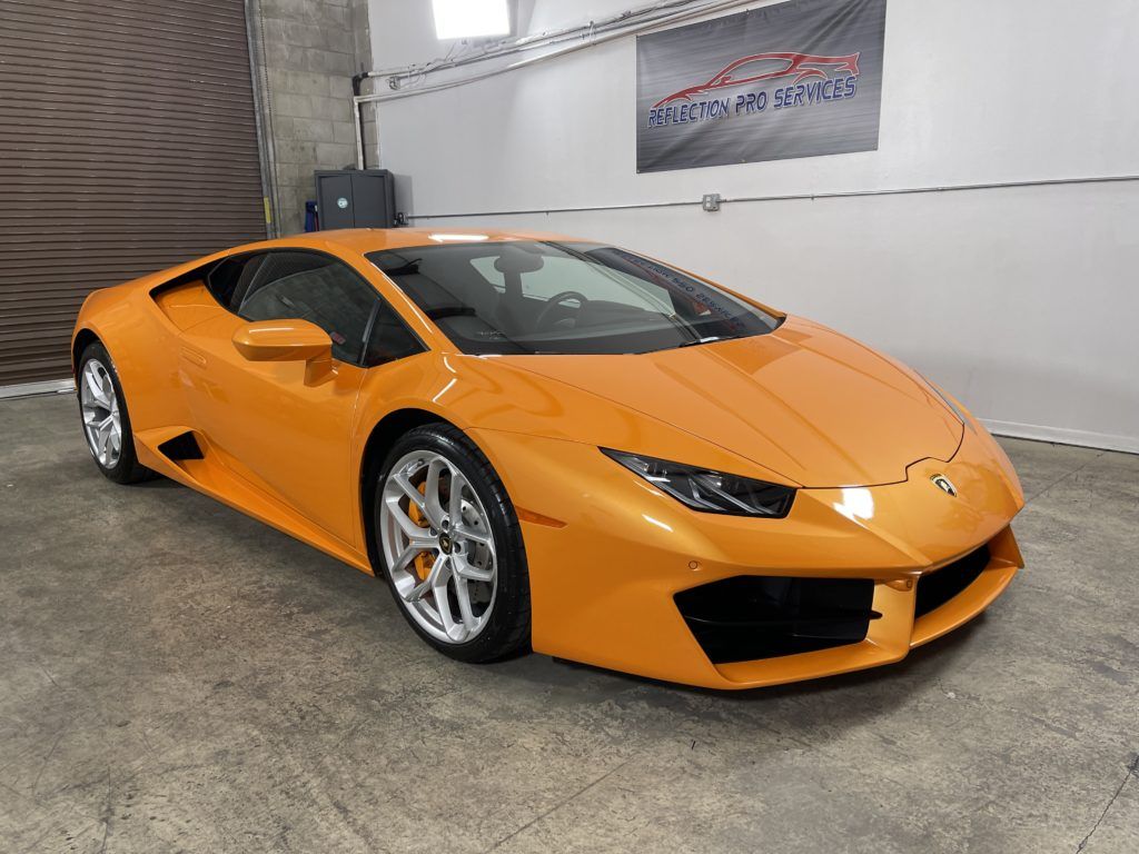 An orange lamborghini huracan is parked in a garage.