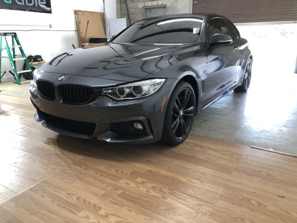 A bmw 4 series is parked in a garage on a wooden floor.