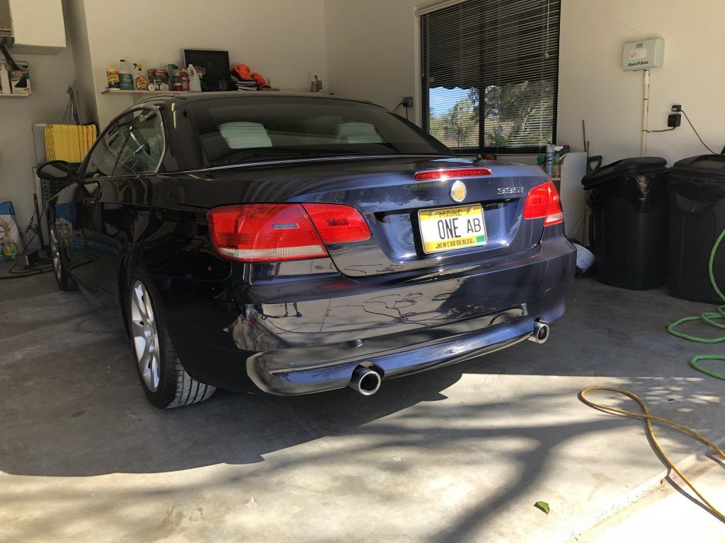 A blue car is parked in a garage with a damaged bumper.