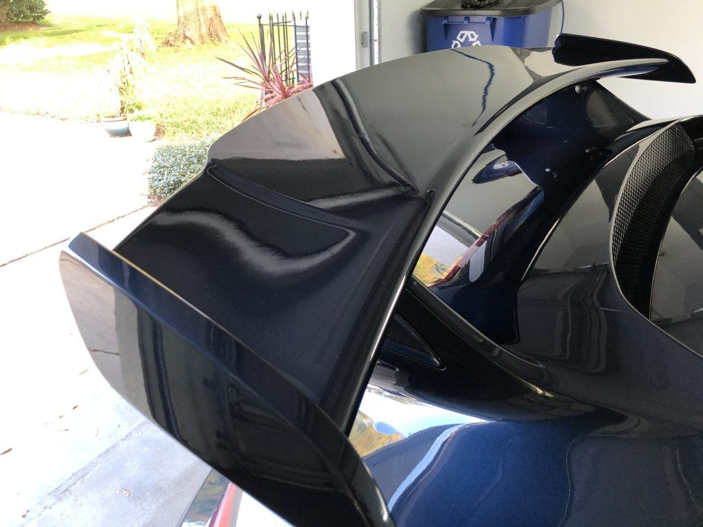 A black car is parked in a garage with the rear window open