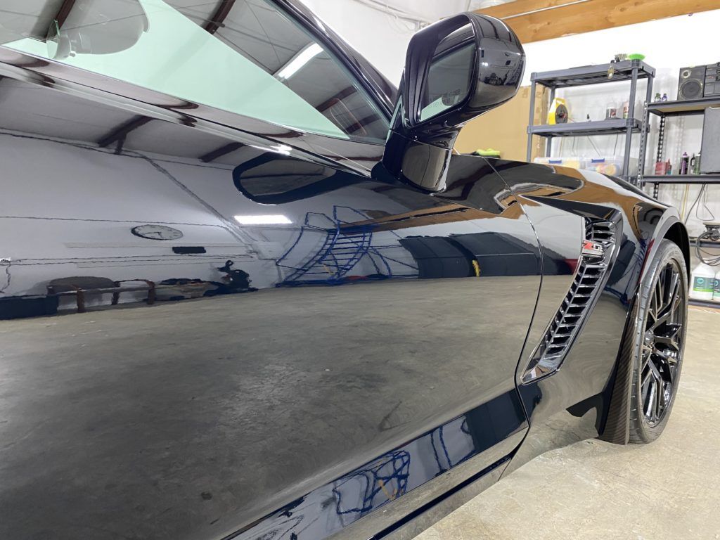 A black sports car is parked in a garage.