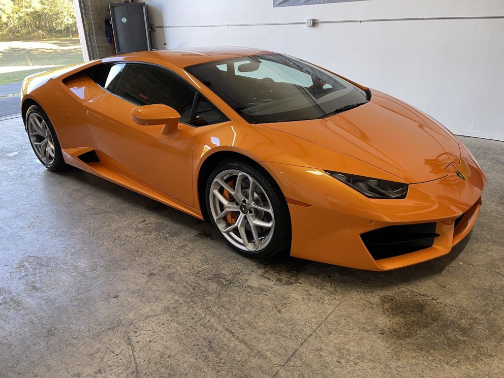 An orange lamborghini huracan is parked in a garage.