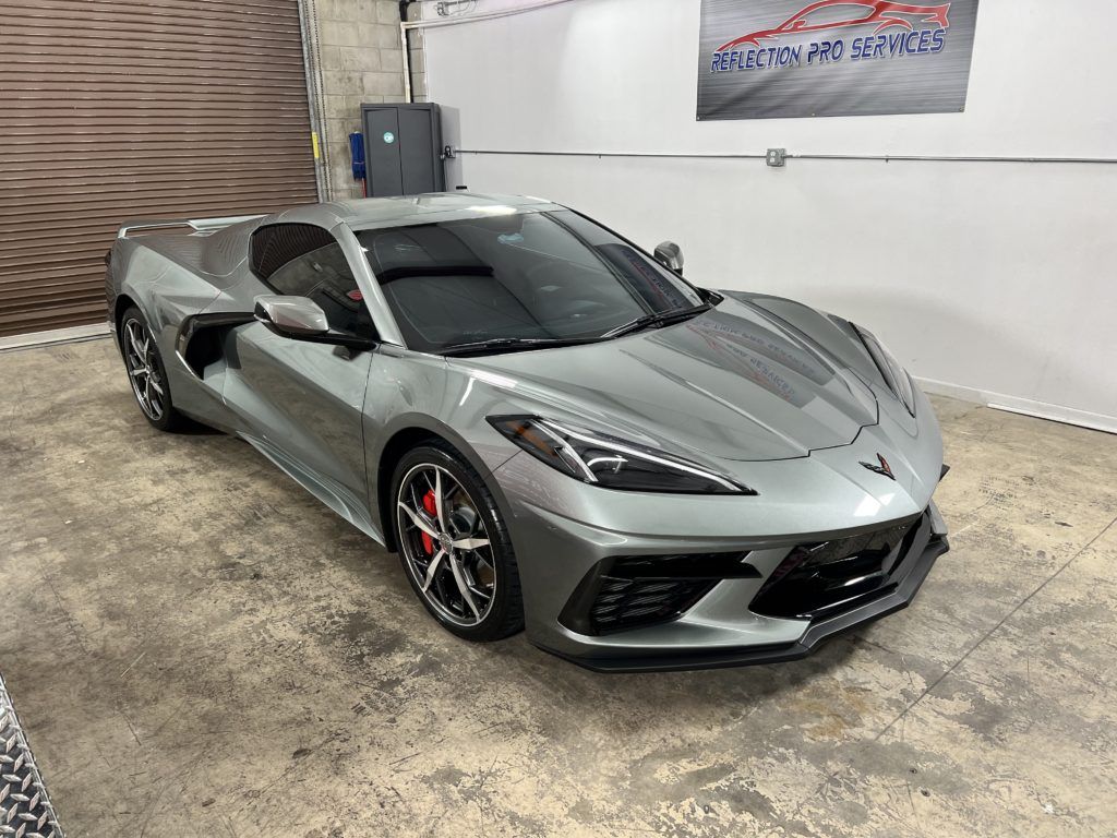A silver corvette is parked in a garage.