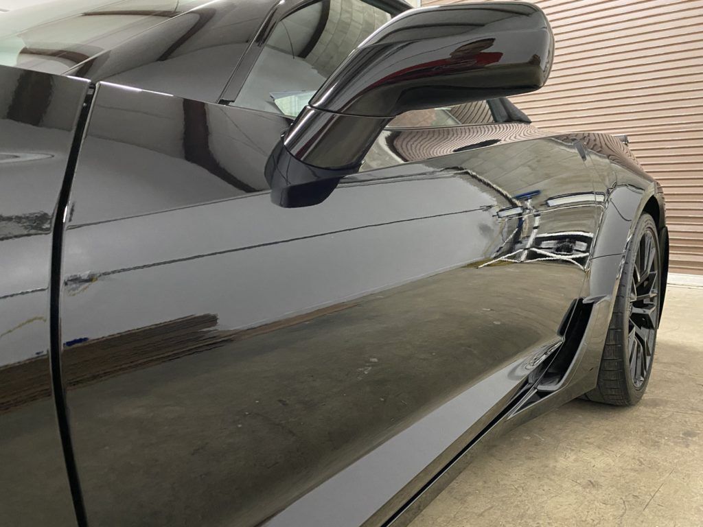 A black sports car is parked in a garage.