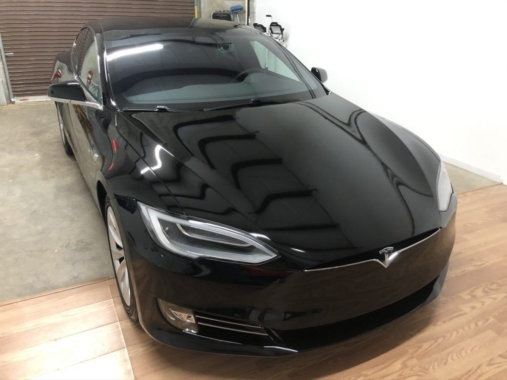 A black tesla model s is parked in a garage.
