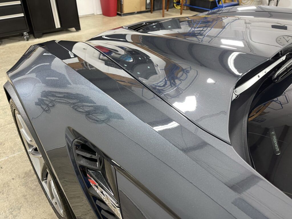 A close up of a car 's hood in a garage.