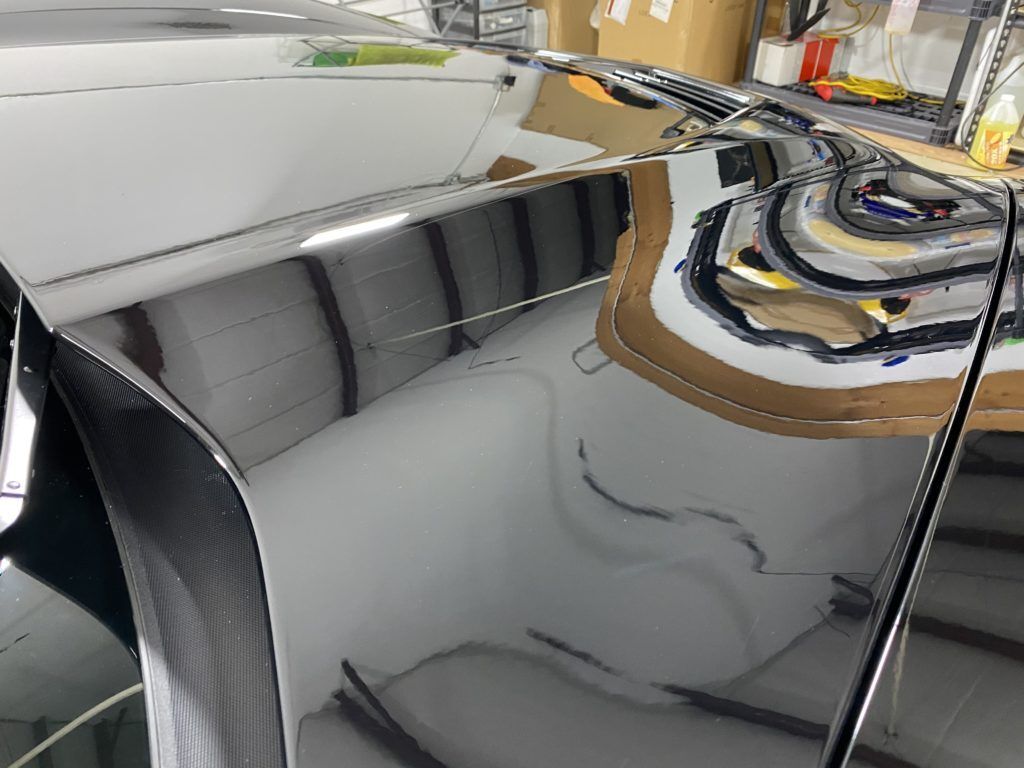 A close up of a car door with a reflection of a building in it.