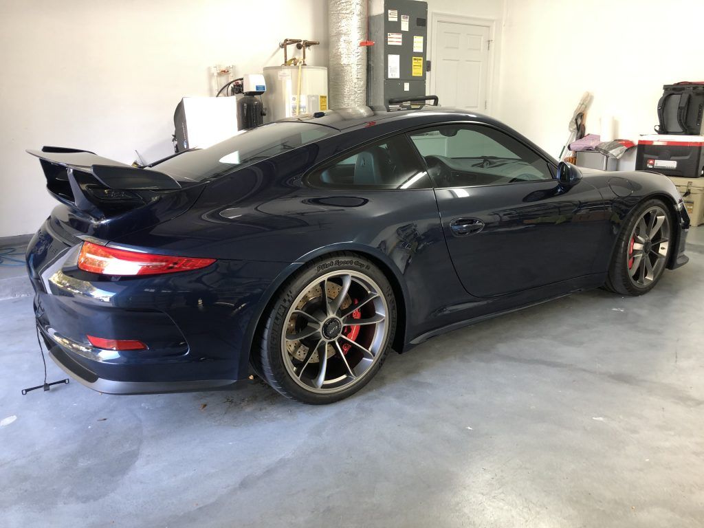 A black porsche 911 gt3 is parked in a garage.