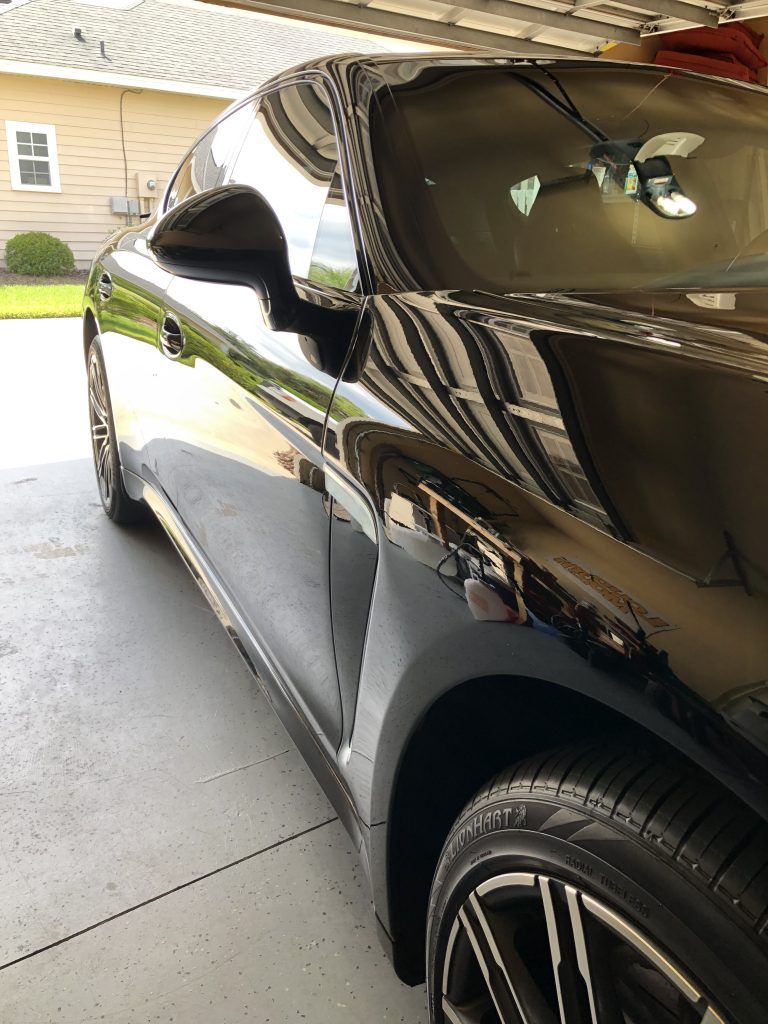 A black car is parked in a garage next to a house.