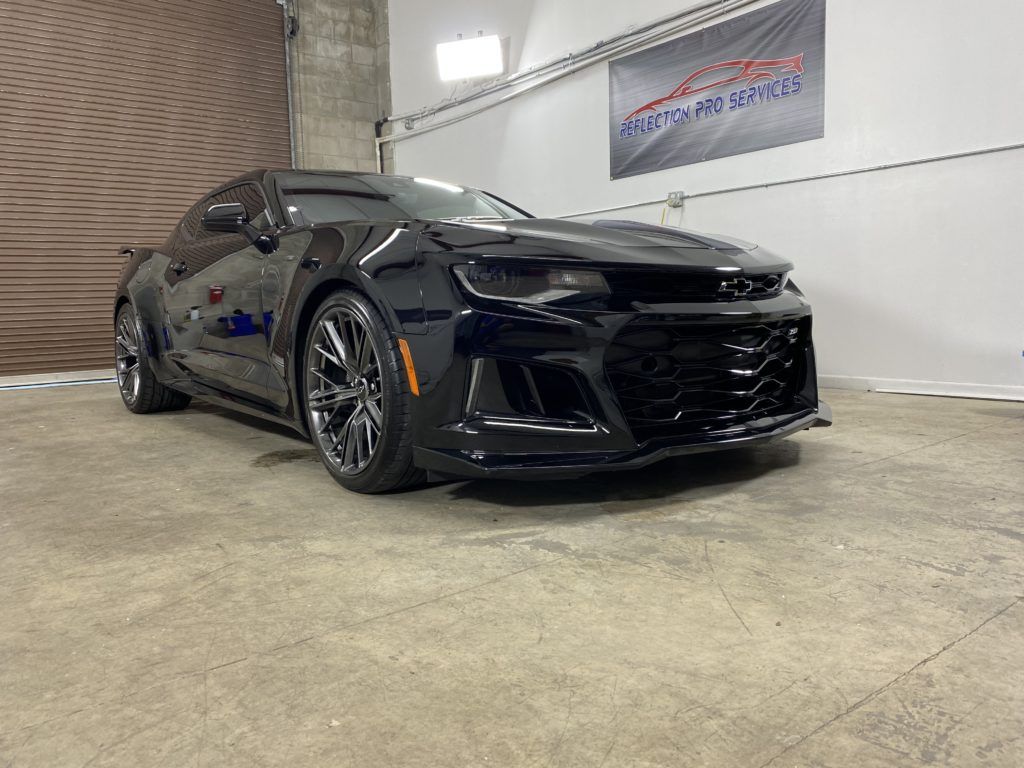 A black chevrolet camaro zl1 is parked in a garage.