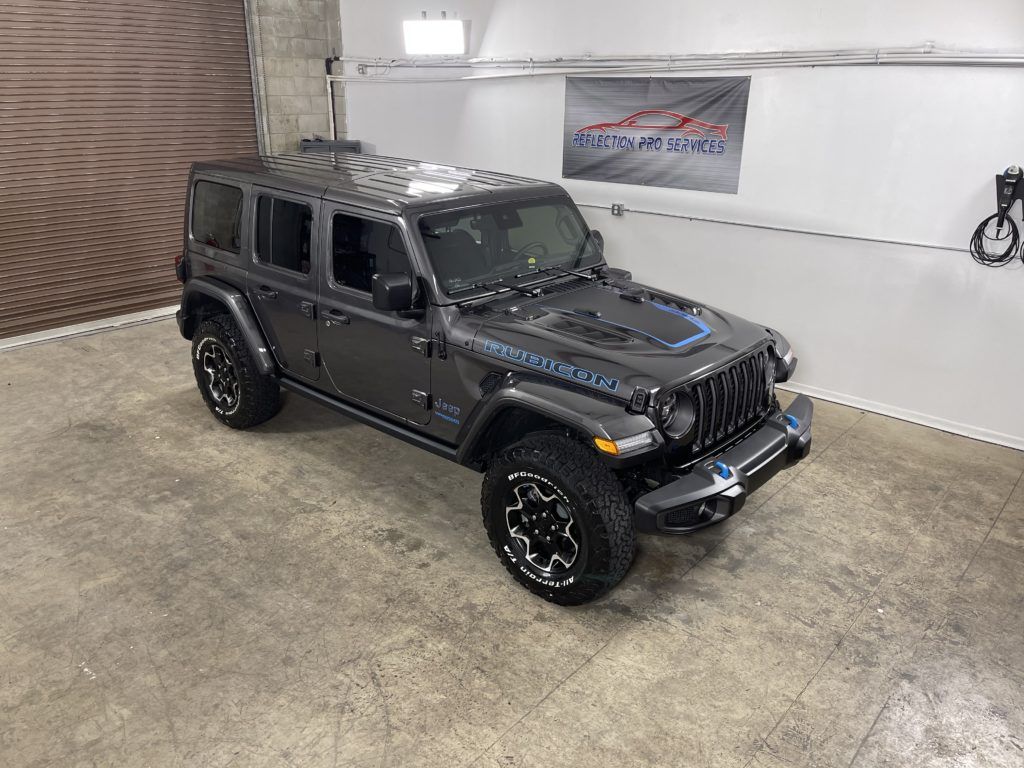 A jeep wrangler is parked in a garage next to a wall.