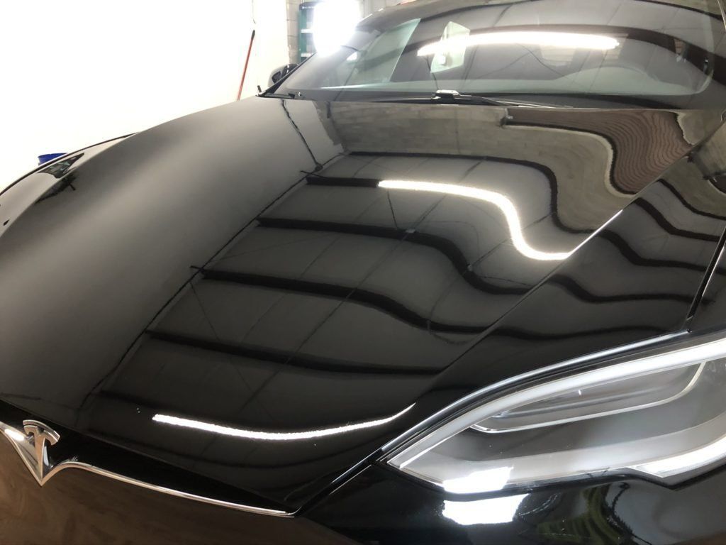 A close up of a black car 's hood and headlights