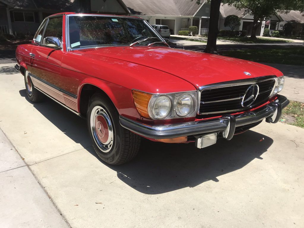 A red mercedes benz sl500 is parked on the side of the road.