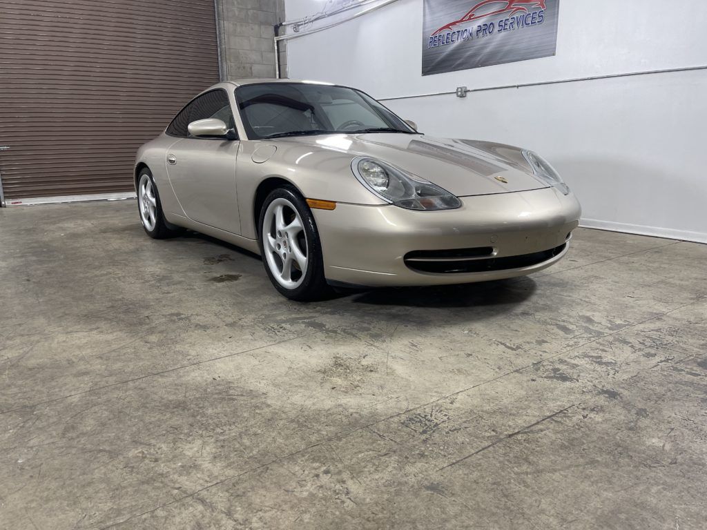 A silver porsche 911 is parked in a garage.