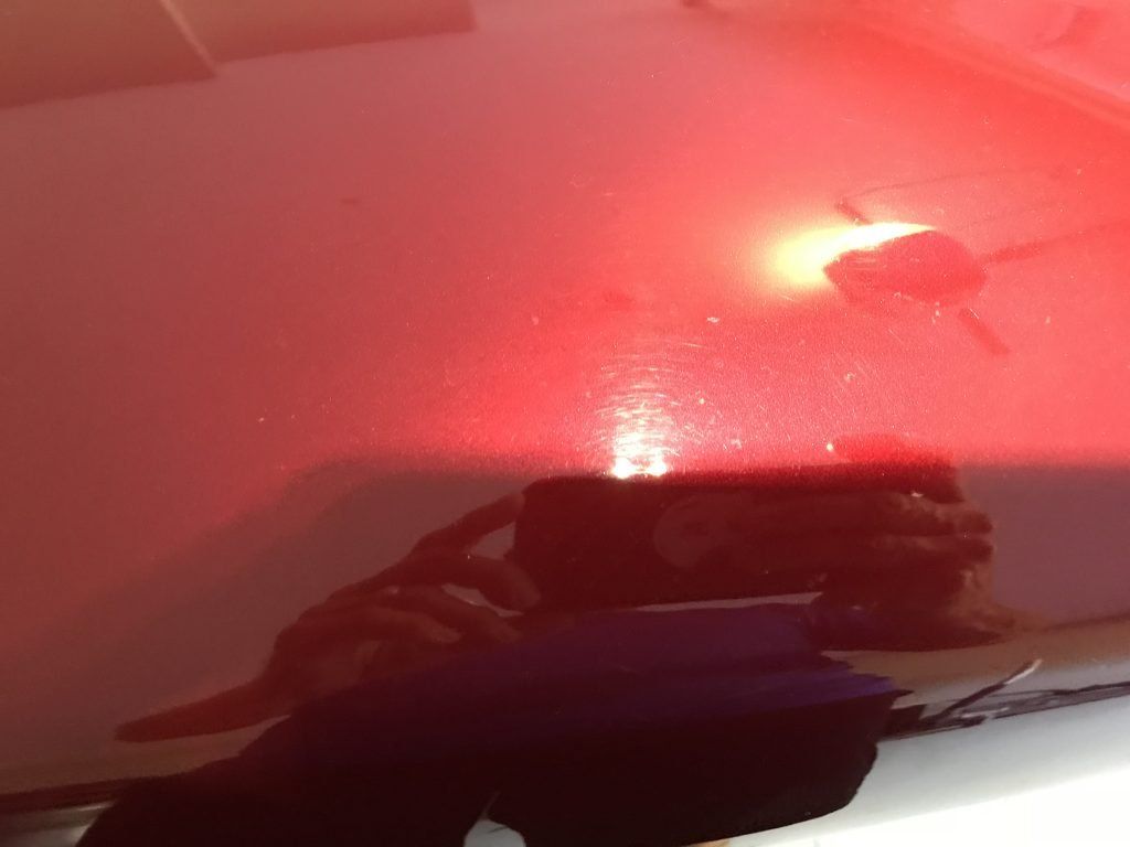 A person is taking a picture of a red car hood