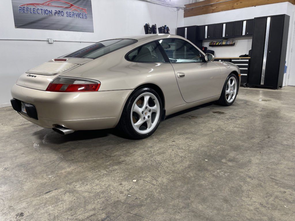A gold porsche 911 is parked in a garage.
