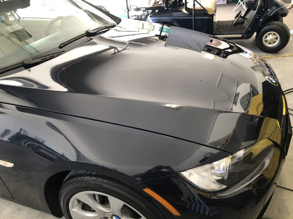 A black car is parked in a garage next to a golf cart.
