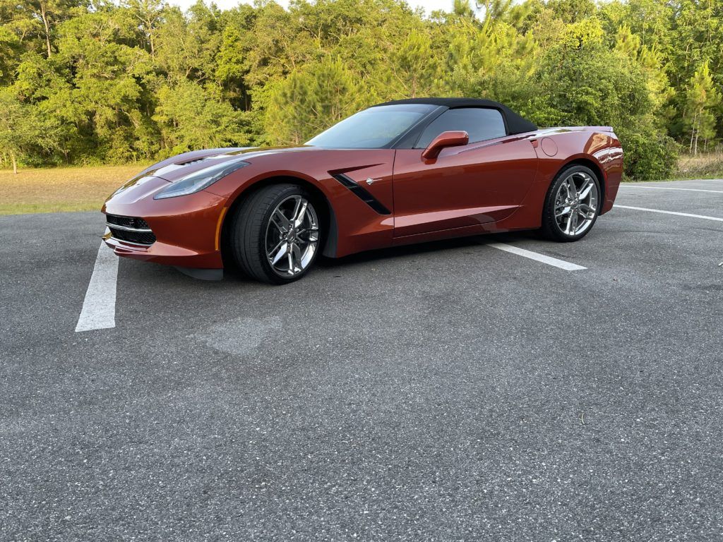 A red corvette convertible is parked in a parking lot.