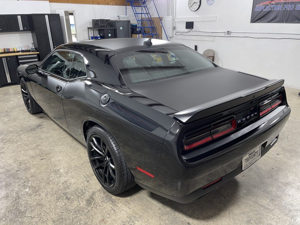 A black dodge challenger is parked in a garage.