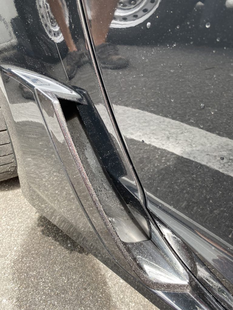 A black car is parked on the side of the road.