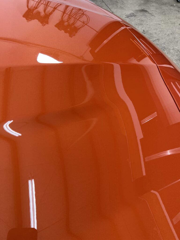 A close up of the hood of an orange car