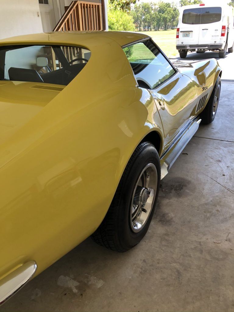 A yellow car is parked in a garage next to a white van