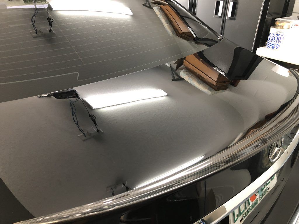 A close up of a car hood with a license plate on it.