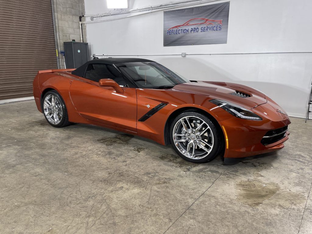 A red corvette convertible is parked in a garage.