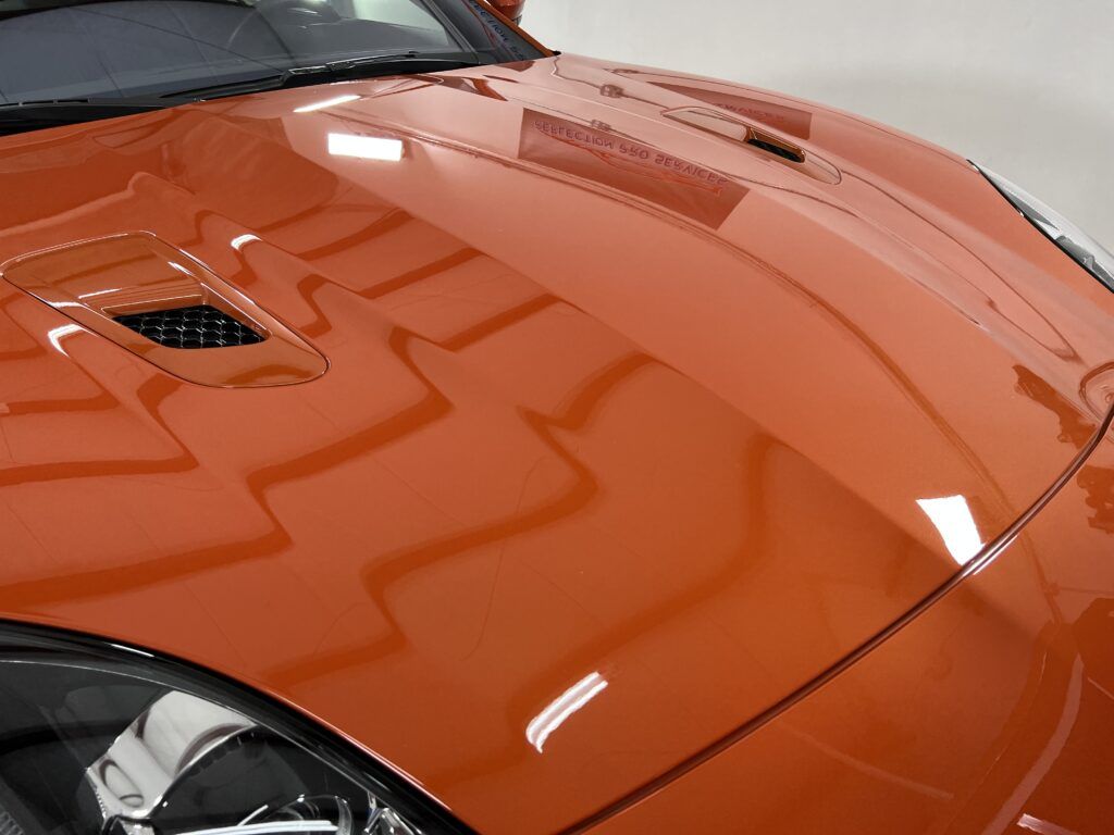 A close up of the hood of an orange sports car