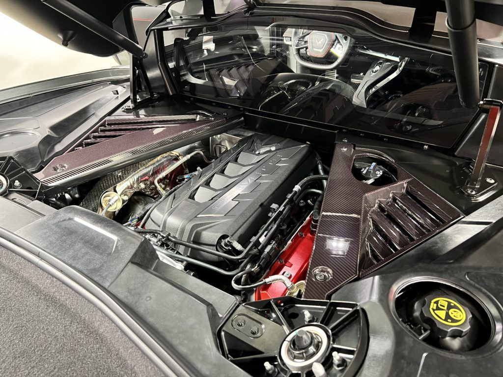 A close up of the engine of a car with the hood open.