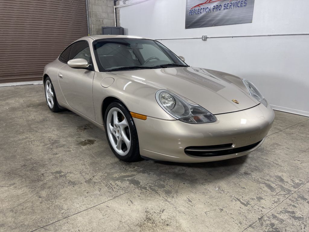 A gold porsche 911 is parked in a garage.