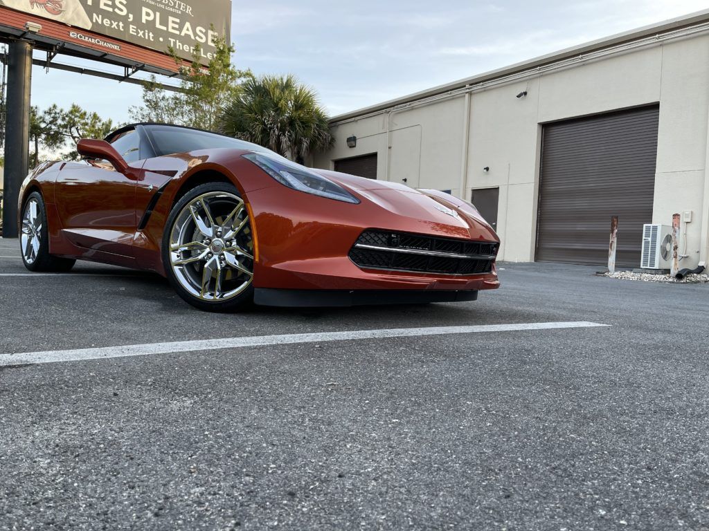 A red sports car is parked in a parking lot in front of a building.